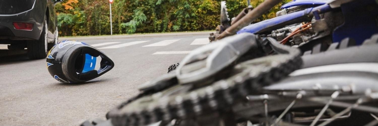 Crashed motorcycle and helmet on the road showing a scene where car insurance is claimed